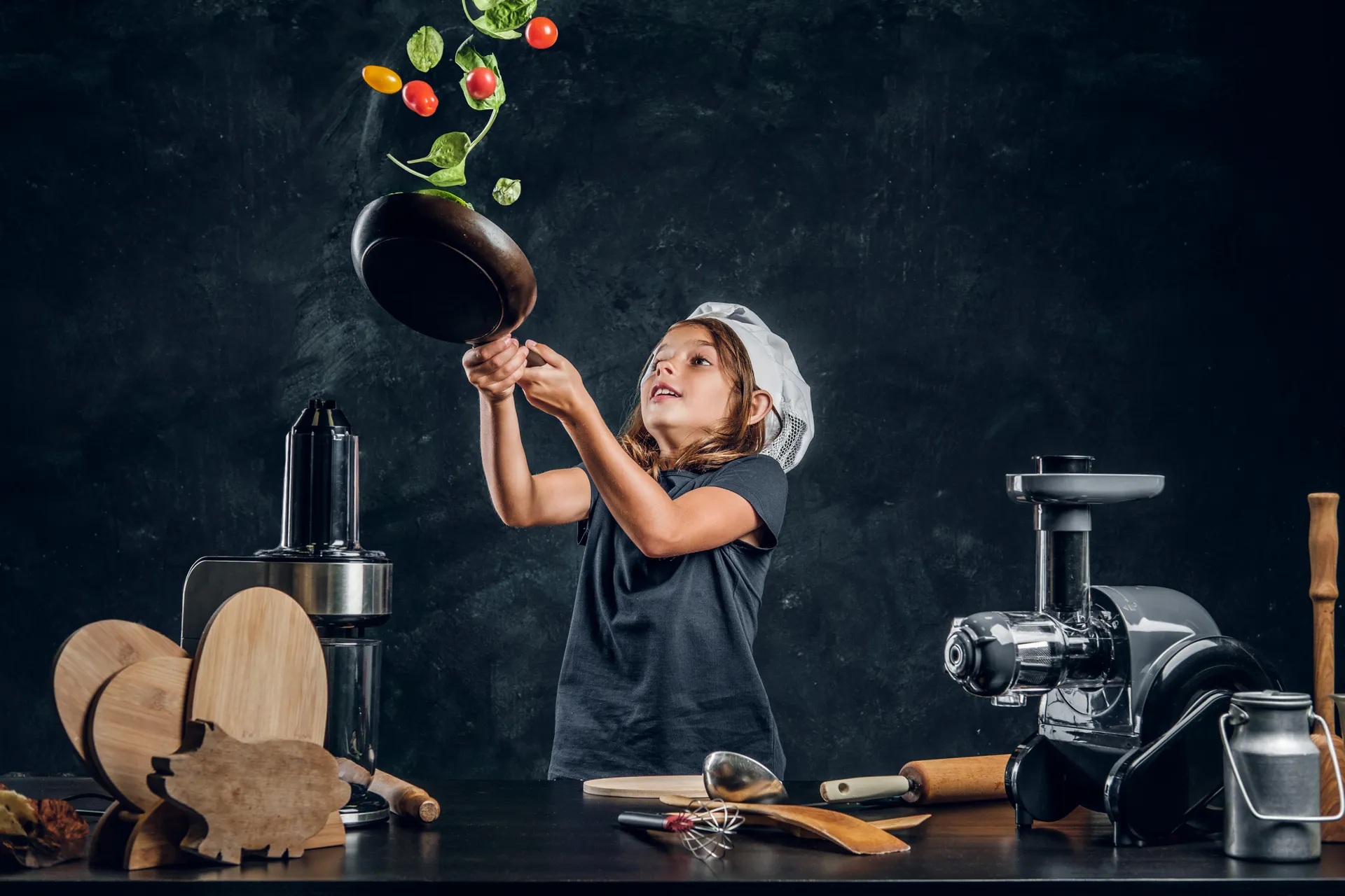 cheerful-girl-is-tossing-vegetables-pan-dark-photo-studio
